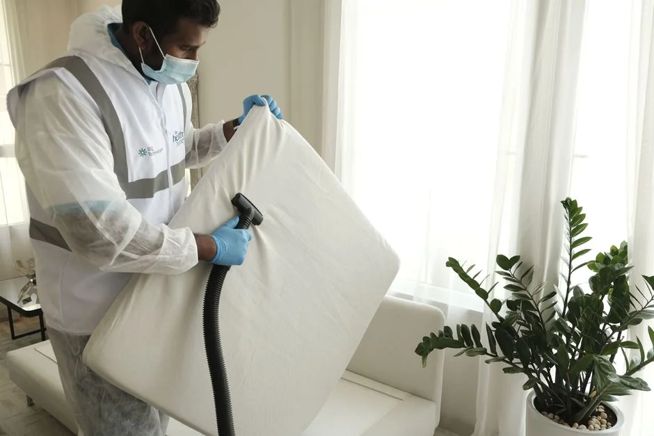 services-03 Minimalist room with a person cleaning a chair using a sponge and cleaning product.